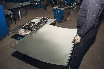 金属板材在工人手, 金工设备工具在工业工厂照片